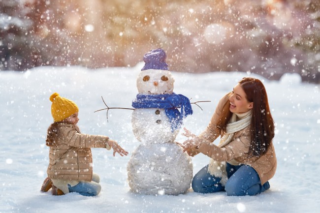Mutter und Kind bauen einen Schneemann © Shutterstock